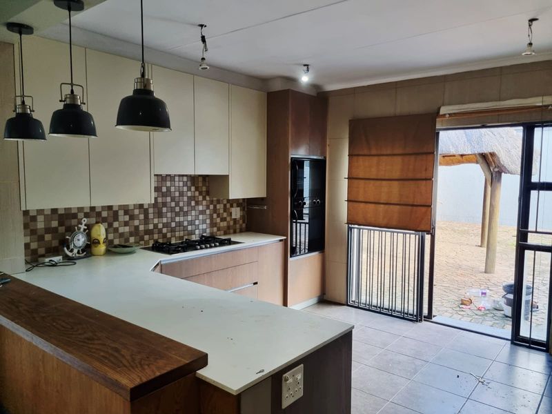 A functional kitchen featuring built-in cabinetry, a gas hob, and an integrated oven, with direct access to an outdoor patio area.