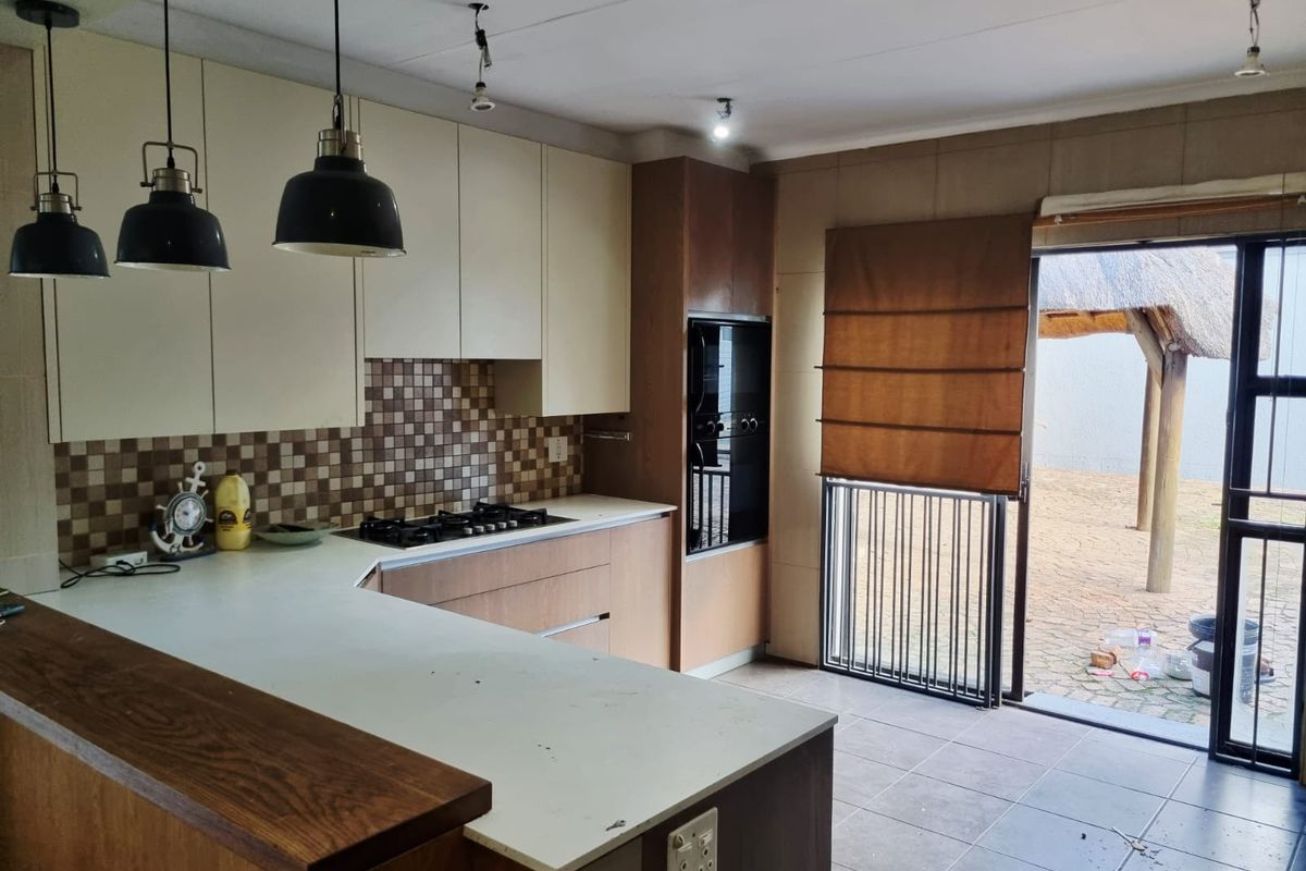 A functional kitchen featuring built-in cabinetry, a gas hob, and an integrated oven, with direct access to an outdoor patio area.