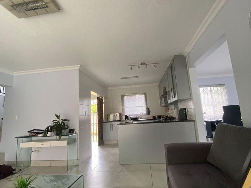 Open-plan living area featuring a modern kitchen with island, tiled flooring, and neutral wall finishes, creating a bright and functional living space.