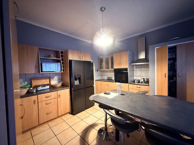 A functional kitchen featuring wood-finish cabinetry, tiled flooring, a built-in oven, and an extractor fan, providing a practical workspace for daily cooking.