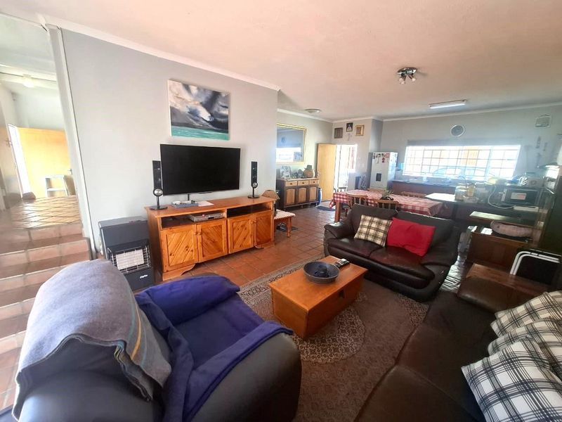 Open-plan living and kitchen area featuring terracotta floor tiles and functional cabinetry, offering a spacious layout suitable for family living.