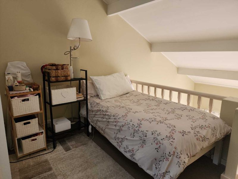 A cozy loft-style bedroom featuring a sloped ceiling with exposed rafters and a protective balustrade overlooking the lower level.