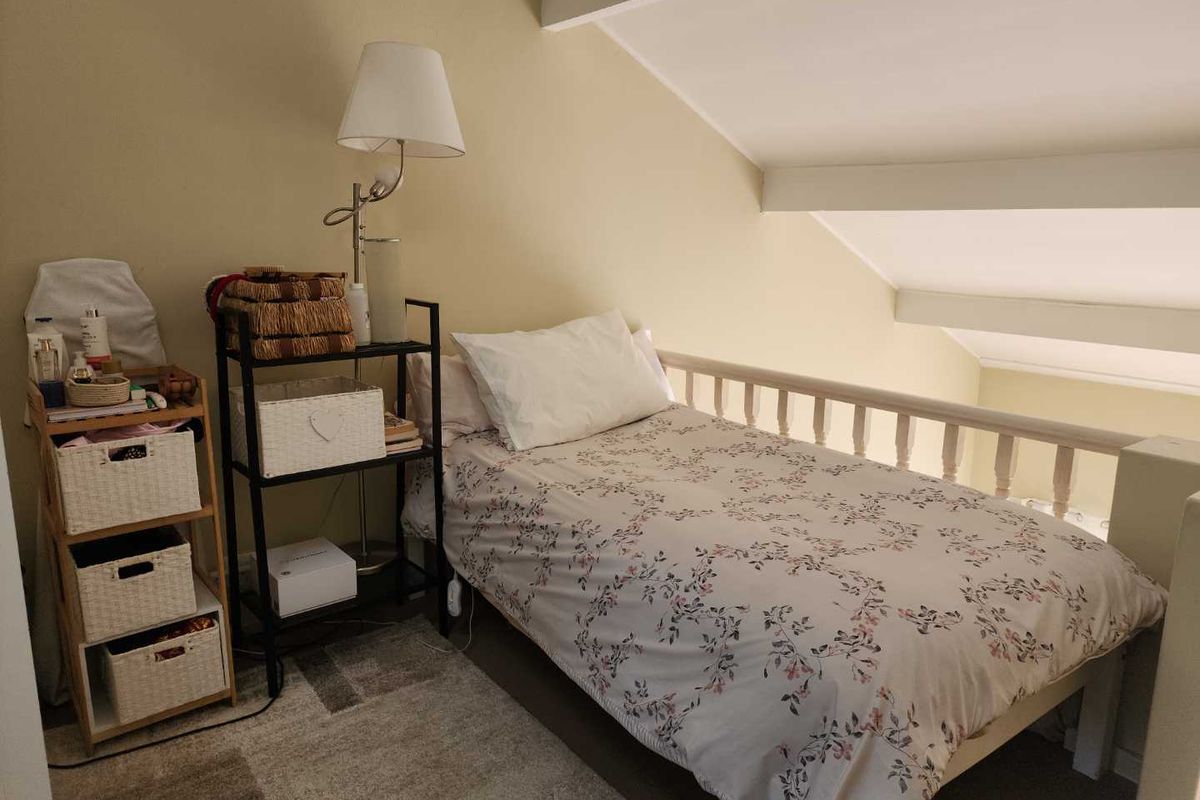 A cozy loft-style bedroom featuring a sloped ceiling with exposed rafters and a protective balustrade overlooking the lower level.