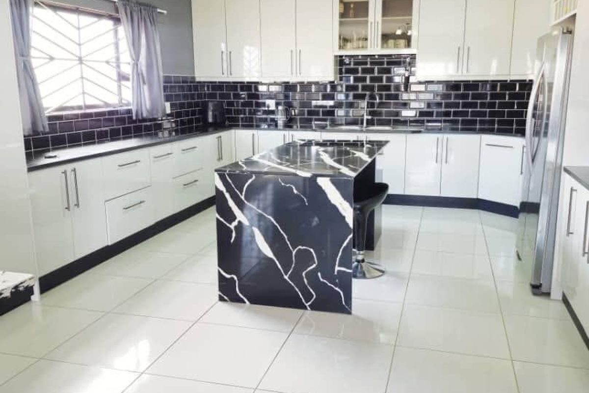 Modern kitchen featuring high-gloss white cabinetry, a striking black and white marble-look island, subway tile backsplash, and large format ceramic floor tiles.
