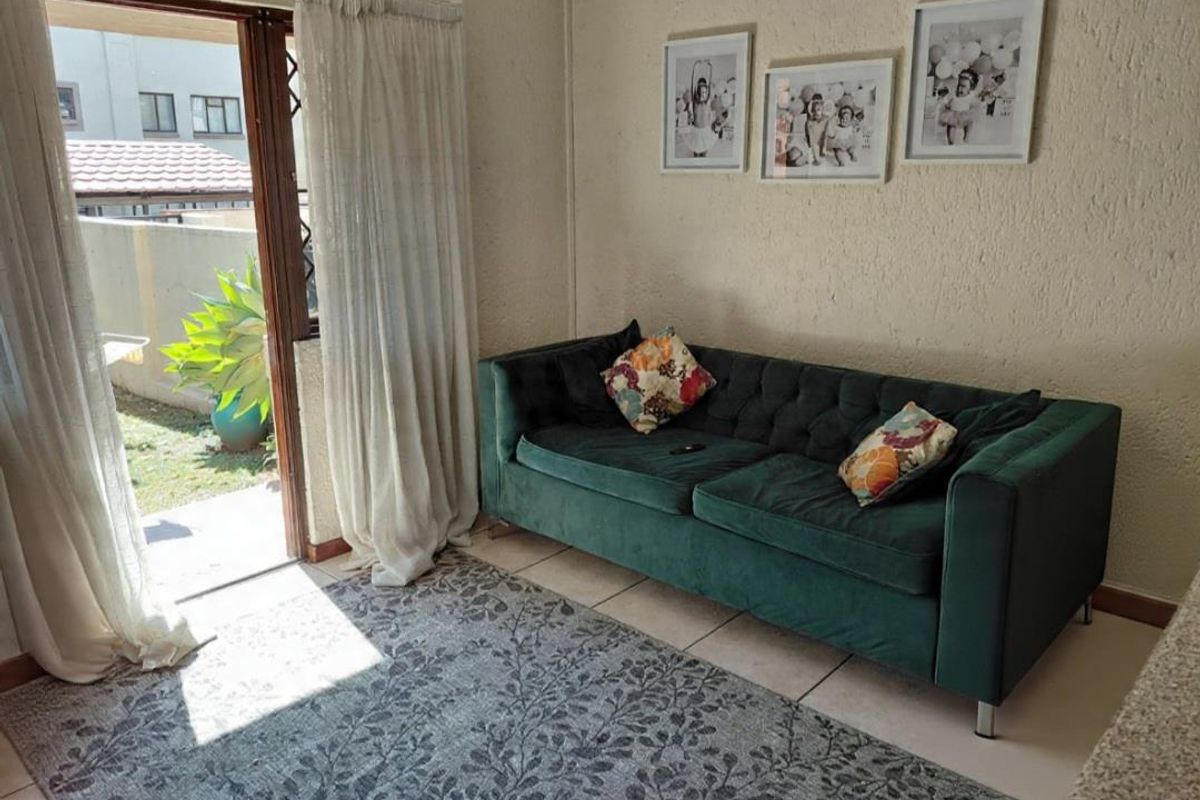 A living room area featuring tiled floors, textured walls, and a sliding glass door providing direct access to the outdoor garden space.