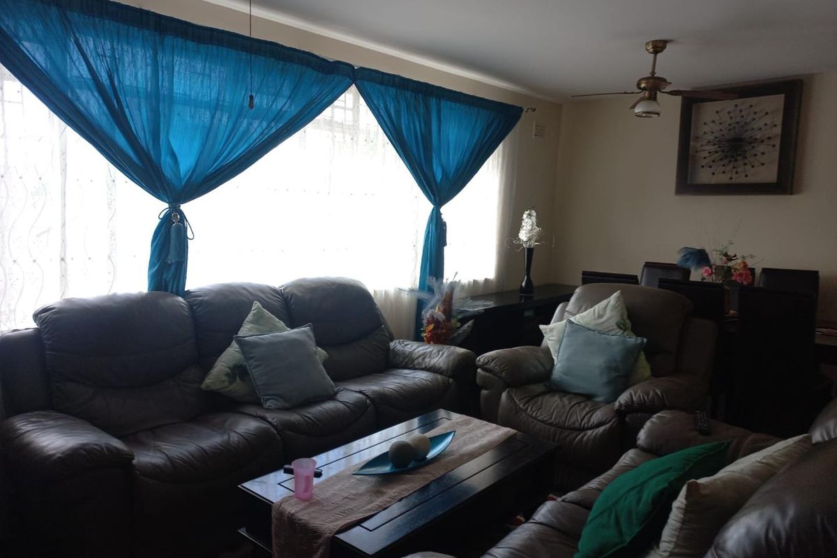 A comfortable living room featuring large windows with natural light, ceiling fans, and neutral wall finishes.
