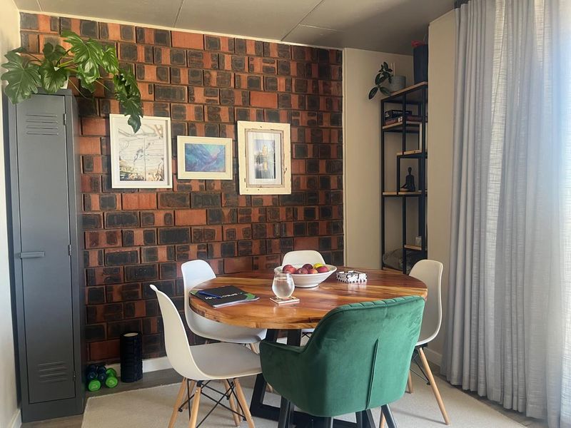 A dining area featuring a distinctive exposed brick feature wall and floor-to-ceiling curtains, providing a warm and textured aesthetic.