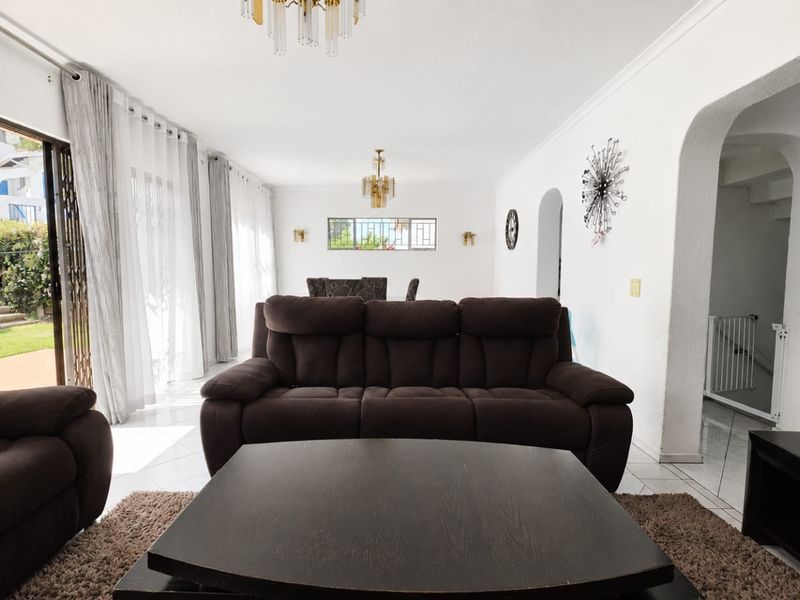Spacious living room featuring tiled flooring, an arched entryway, and large sliding glass doors that provide natural light and access to the outdoor area.