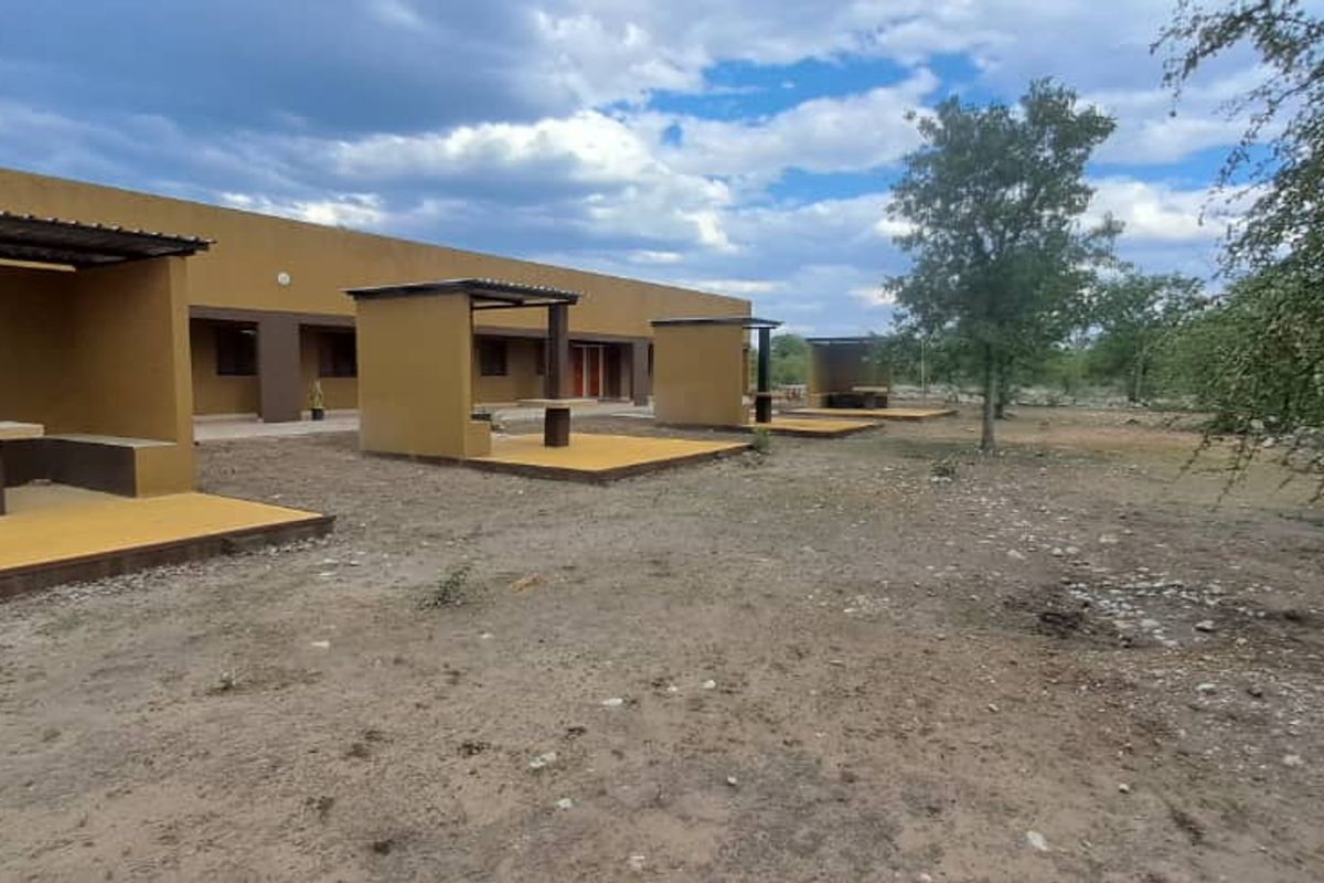 Rear exterior view of the lodge featuring multiple covered patio areas with built-in concrete seating and platforms set against the building facade.