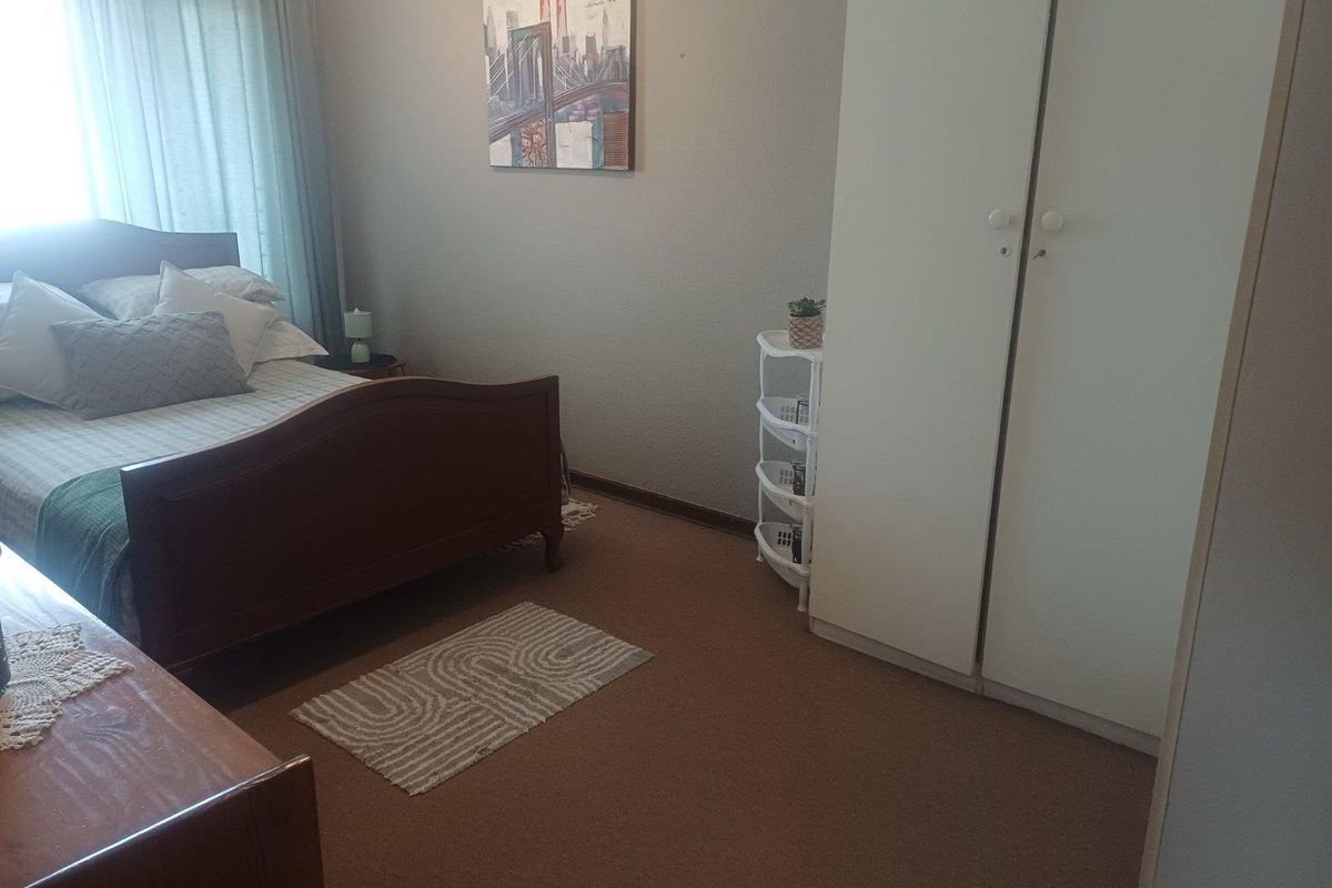 A bedroom featuring neutral wall finishes, carpeted flooring, and a built-in wardrobe.