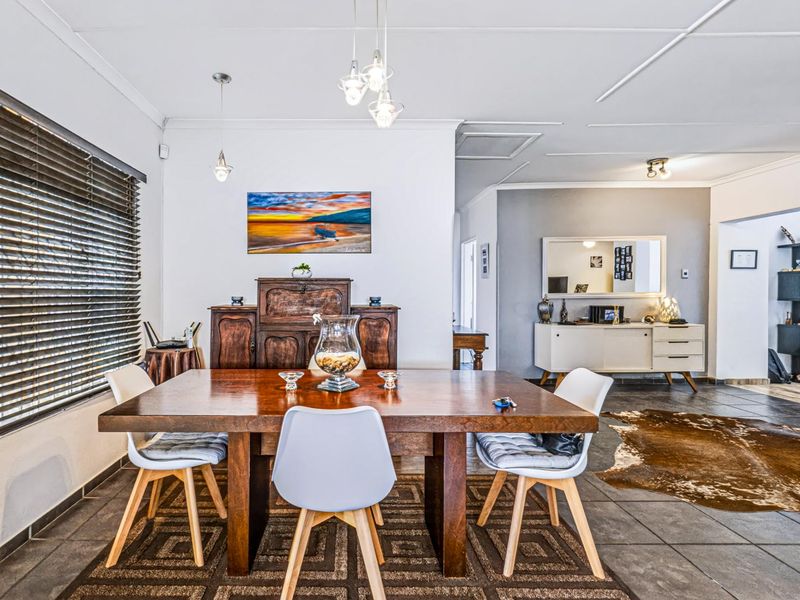 A well-lit dining room featuring tiled flooring, coved ceilings, and large windows with venetian blinds, creating a comfortable and functional space for meals.