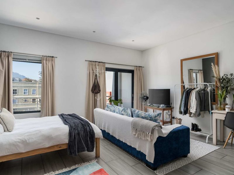 A bright and spacious bedroom featuring tiled flooring, recessed lighting, and direct access to a balcony through a sliding glass door.