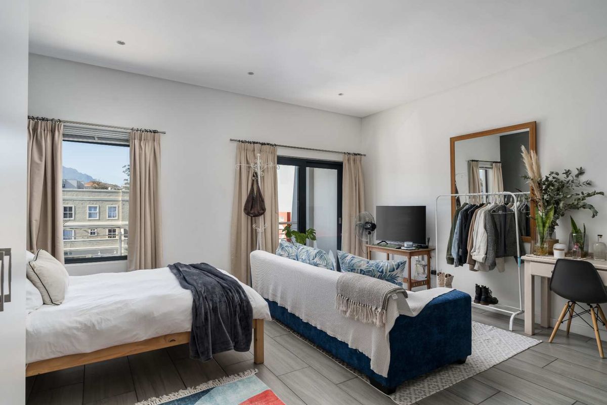 A bright and spacious bedroom featuring tiled flooring, recessed lighting, and direct access to a balcony through a sliding glass door.