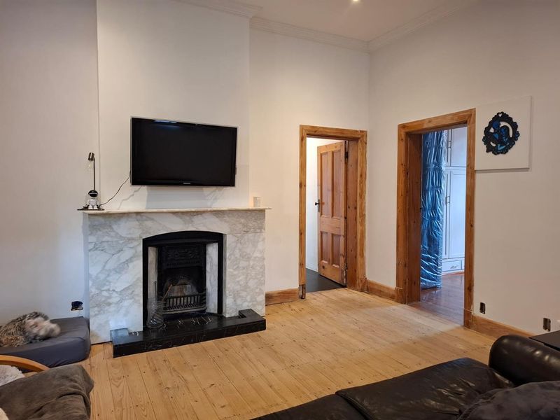 Living room featuring a classic marble fireplace with cast iron insert, original timber flooring, and traditional timber door frames.