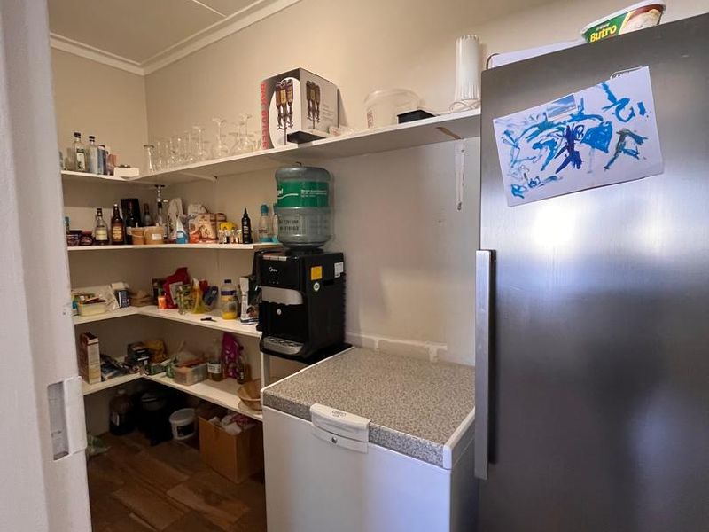 A functional scullery or pantry area featuring built-in open shelving and tiled flooring, providing additional storage and utility space.