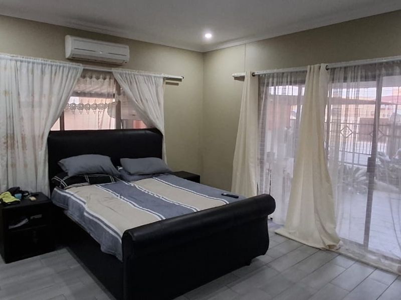 A bedroom featuring tiled flooring, built-in wardrobe, split-system air conditioning, and sliding glass doors providing access to the exterior.
