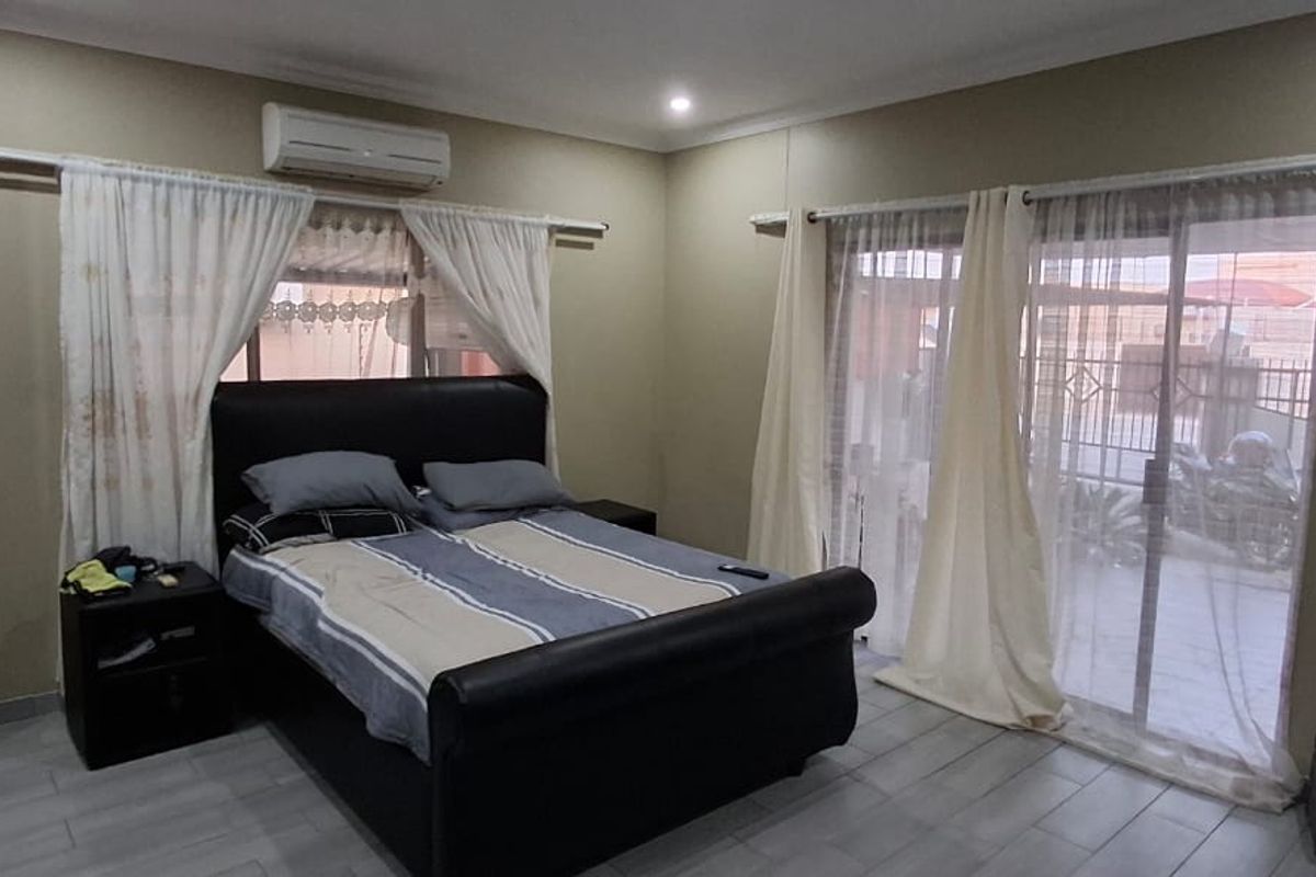 A bedroom featuring tiled flooring, built-in wardrobe, split-system air conditioning, and sliding glass doors providing access to the exterior.