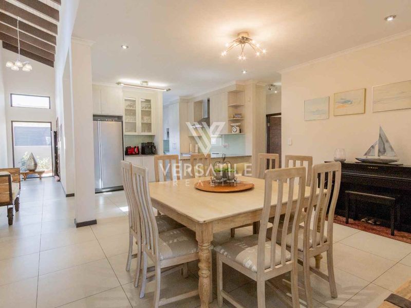 Spacious open-plan living and dining area featuring tiled floors, exposed timber ceiling beams, and a modern kitchen with integrated cabinetry.