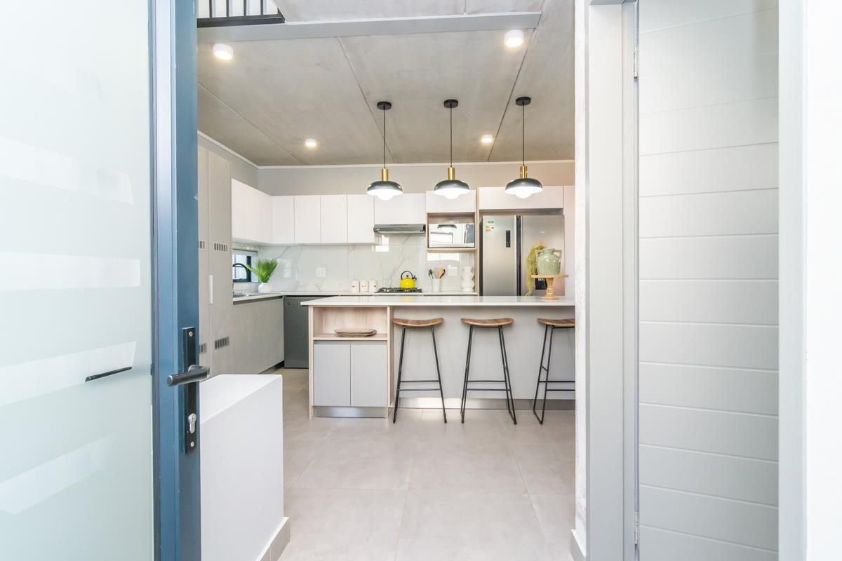 Modern kitchen featuring a central island, sleek cabinetry, quartz countertops, and exposed concrete ceilings, creating a contemporary and functional culinary space.
