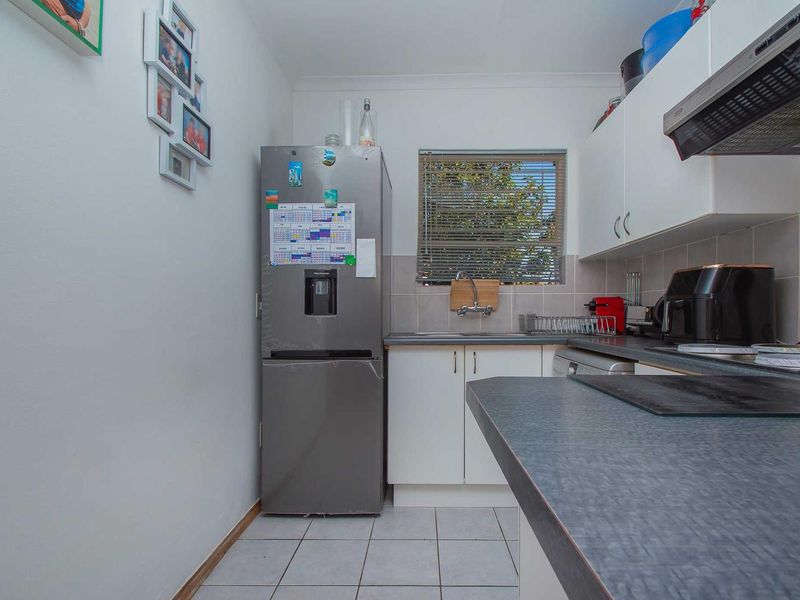 A functional kitchen featuring white cabinetry, laminate countertops, tiled flooring, and a tiled backsplash, providing a practical workspace for daily meal preparation.