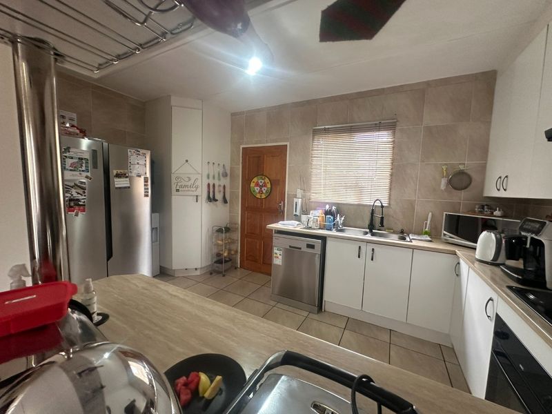 A functional kitchen featuring white cabinetry, tiled backsplash, laminate countertops, and integrated appliances, offering a practical layout for daily meal preparation.