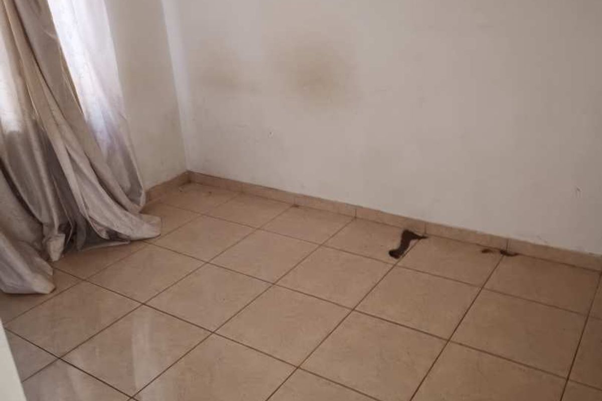 An empty bedroom featuring tiled flooring and neutral walls, requiring minor cosmetic repairs and fresh paint to restore its appeal.
