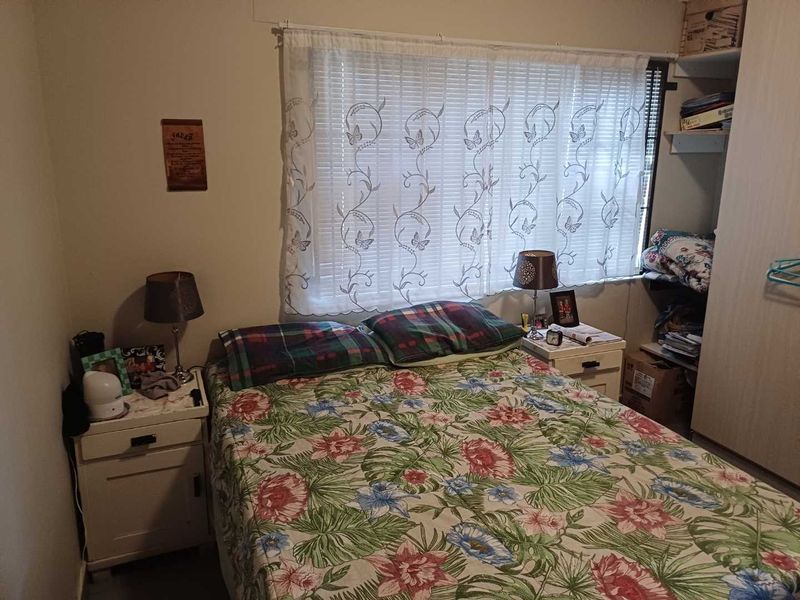 A functional bedroom featuring a built-in wardrobe and window blinds, offering a practical layout for comfortable living.