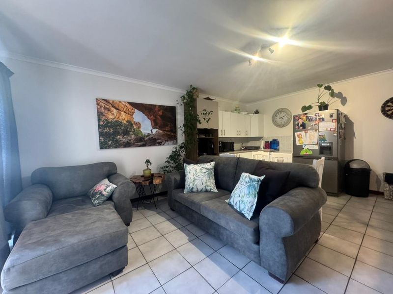Open-plan living area featuring tiled flooring and a functional kitchen with built-in cabinetry, creating a versatile space for relaxation and dining.