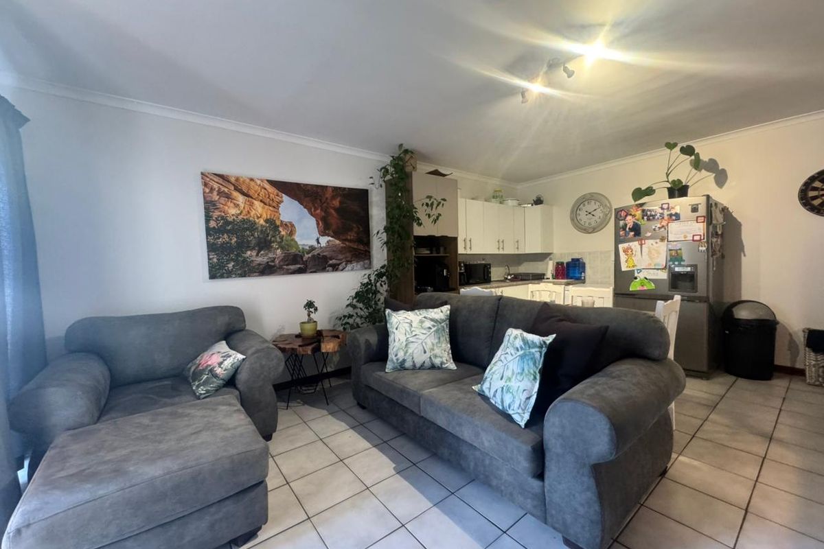 Open-plan living area featuring tiled flooring and a functional kitchen with built-in cabinetry, creating a versatile space for relaxation and dining.