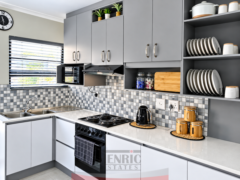 Modern kitchen featuring grey cabinetry, quartz countertops, mosaic tile backsplash, and integrated appliances including a gas hob and built-in oven.