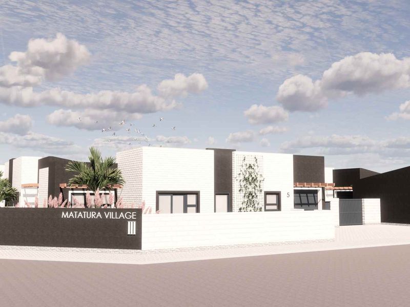 A modern townhouse development exterior featuring clean architectural lines, paved driveways, and secure garage access at Matatura Village.