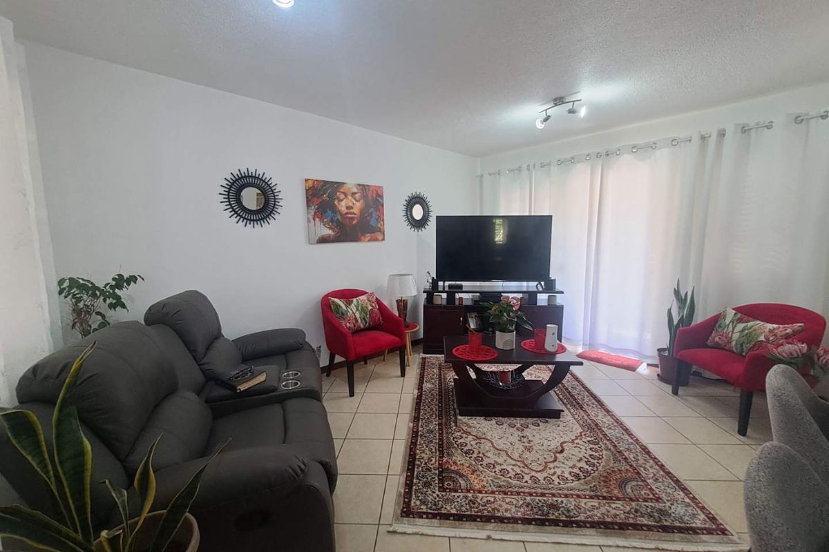 A comfortable living room featuring tiled flooring and large sliding glass doors that provide access to the outdoor area.