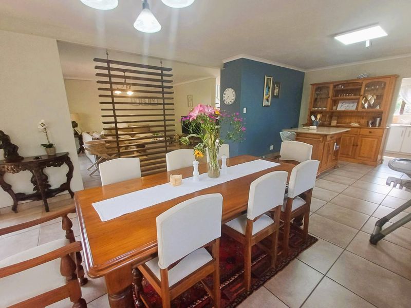 Open plan dining area featuring tiled flooring, a decorative timber room divider, and built-in wooden cabinetry, creating a functional and connected living space.