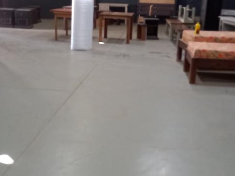 Spacious industrial utility area featuring high ceilings with exposed steel trusses, concrete flooring, and functional overhead lighting.