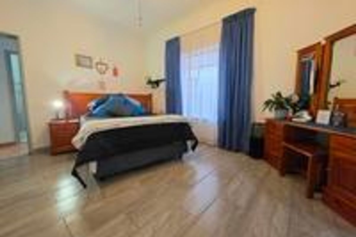 A bedroom featuring wood-look tile flooring, a ceiling fan, and a window with curtains.
