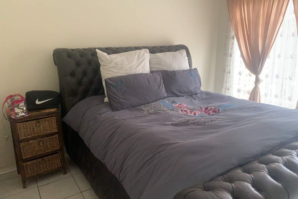 A bedroom featuring tiled flooring and a window with curtain treatments.