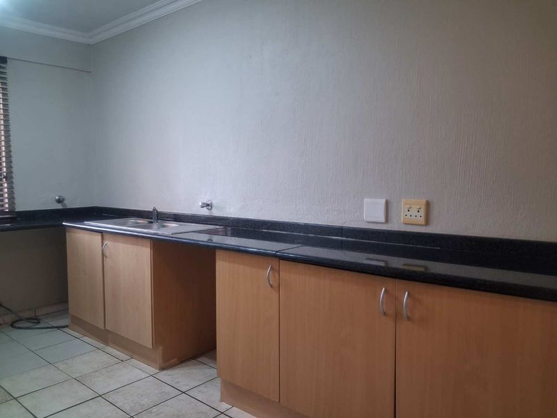A functional kitchen space featuring laminate cabinetry, granite countertops, and a stainless steel sink, offering a clean canvas for potential updates.