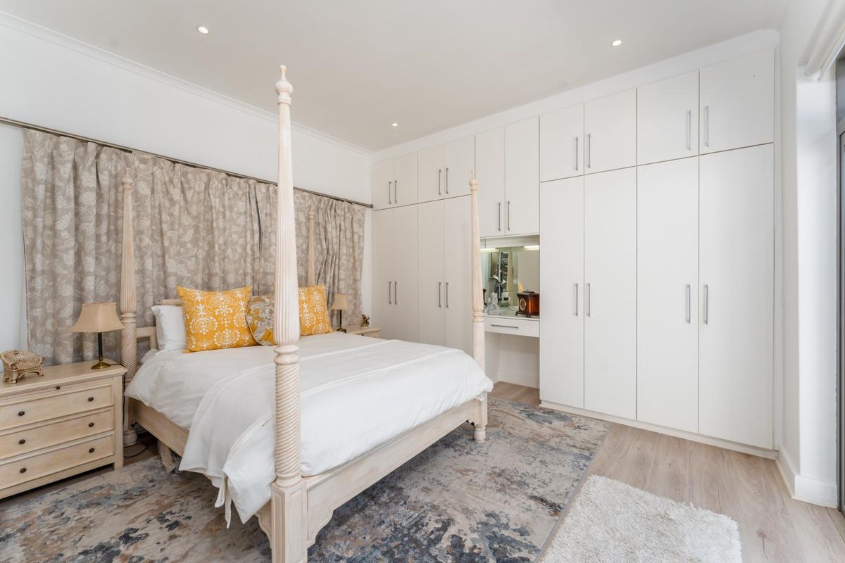 A well-maintained bedroom featuring extensive floor-to-ceiling built-in cabinetry with an integrated vanity area and recessed ceiling lighting.