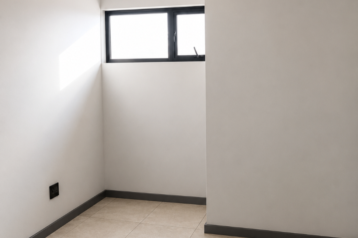 A clean, empty bedroom featuring neutral tiled flooring, recessed downlighting, and a modern aluminium-framed window.