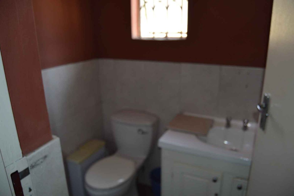 A compact office bathroom featuring a standard toilet and a small vanity basin with built-in cabinetry.