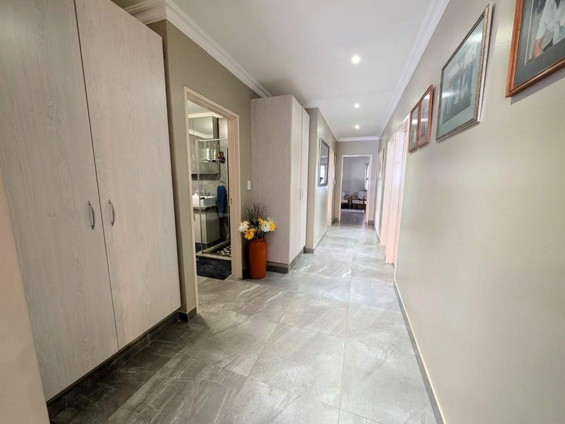 A well-maintained hallway featuring modern large-format floor tiles, built-in storage cupboards, and recessed ceiling lighting.