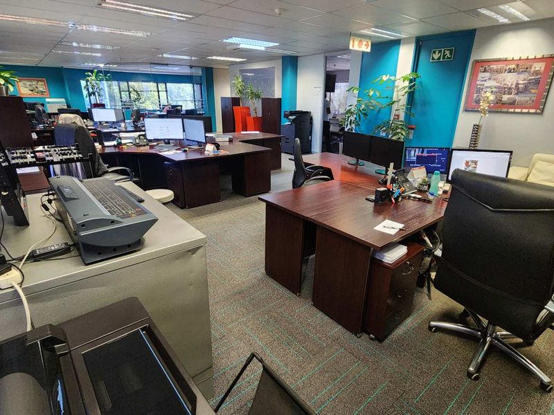Open-plan office space featuring suspended ceilings, recessed lighting, and carpeted flooring, providing a functional workspace environment.