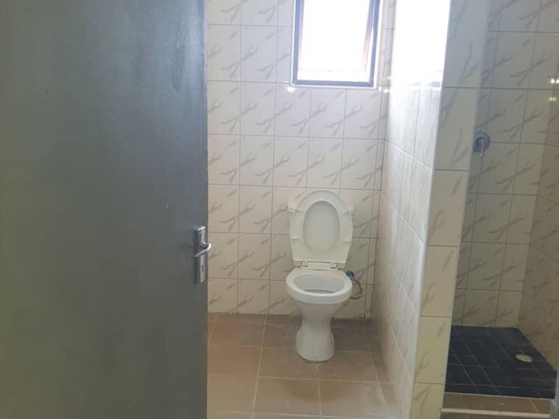 A functional bathroom featuring a toilet and a walk-in shower with tiled walls and flooring.