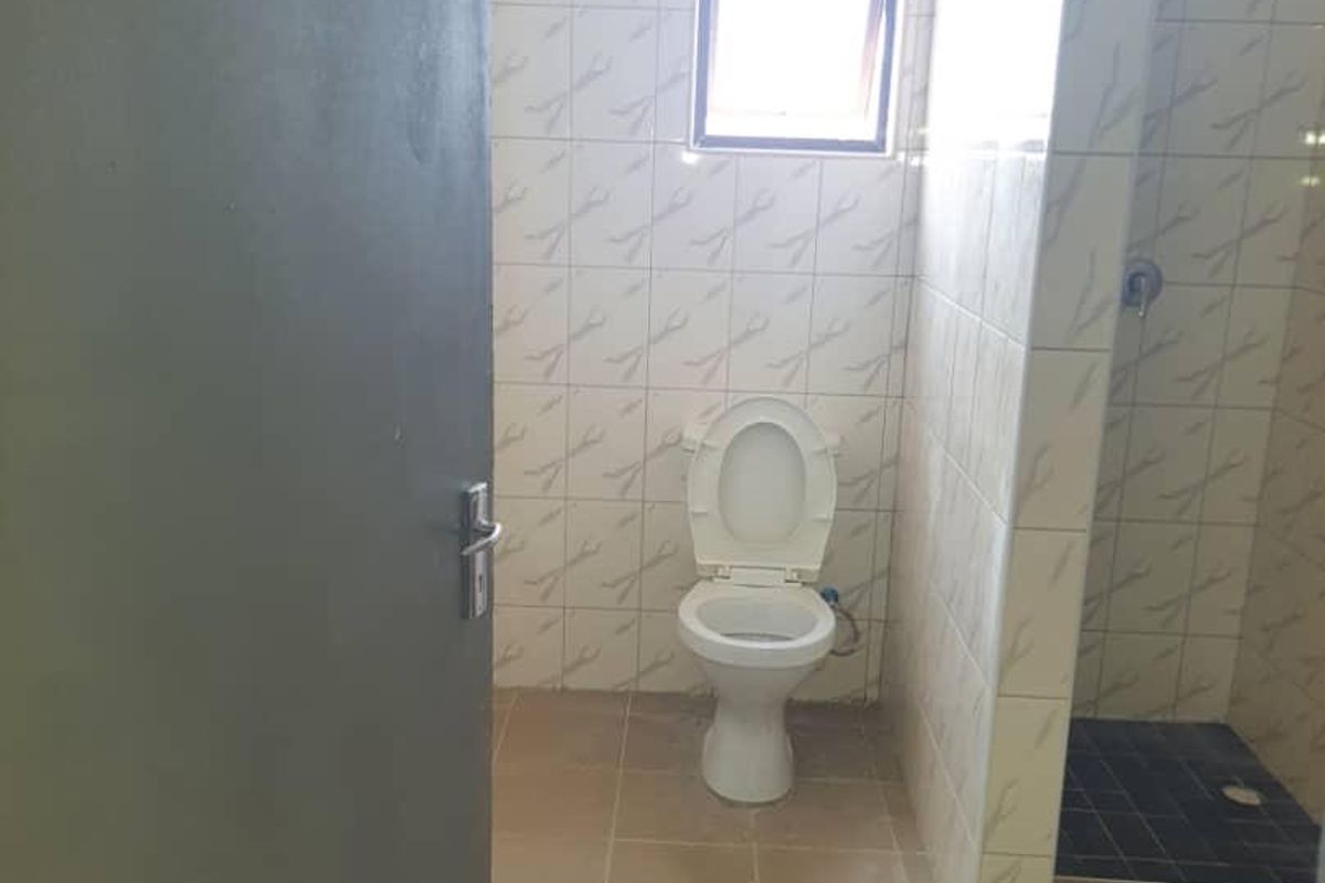 A functional bathroom featuring a toilet and a walk-in shower with tiled walls and flooring.