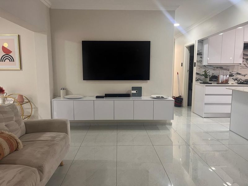 Modern open-plan living area featuring high-gloss floor tiles, sleek built-in cabinetry, and a contemporary kitchen with marble-effect finishes.