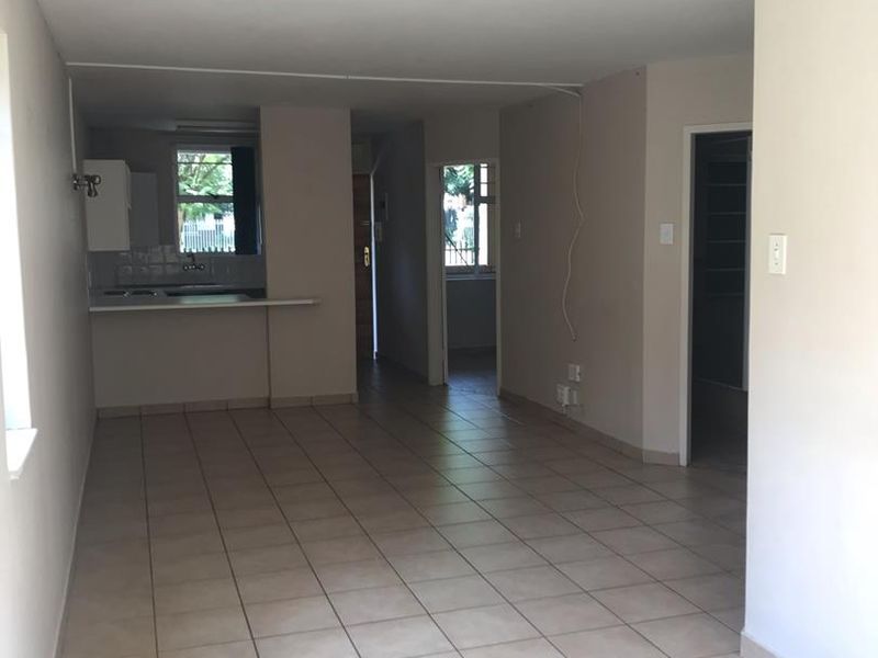 An open-plan living and kitchen area featuring neutral tiled flooring and a functional kitchen layout, offering a blank canvas for interior design.