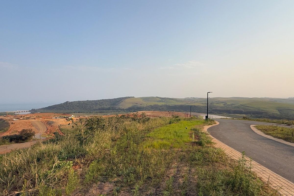 A scenic view overlooking a developing residential estate with paved roads, street lighting, and expansive landscape vistas.