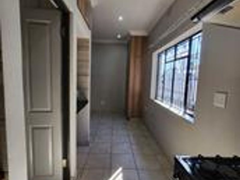 A clean, empty kitchen area featuring tiled flooring, recessed lighting, and built-in cabinetry with a gas stove.