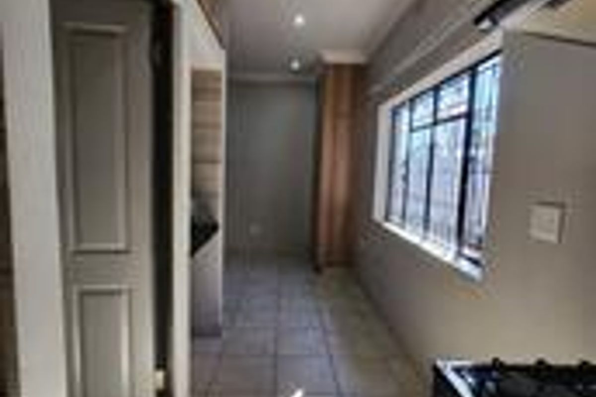A clean, empty kitchen area featuring tiled flooring, recessed lighting, and built-in cabinetry with a gas stove.