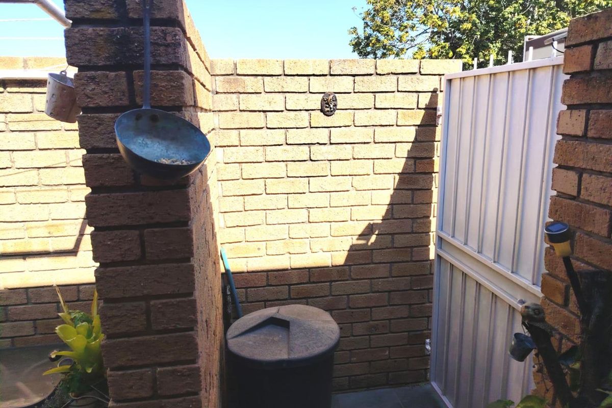 A private outdoor utility area featuring brick boundary walls and a secure metal gate, providing a functional and enclosed space.
